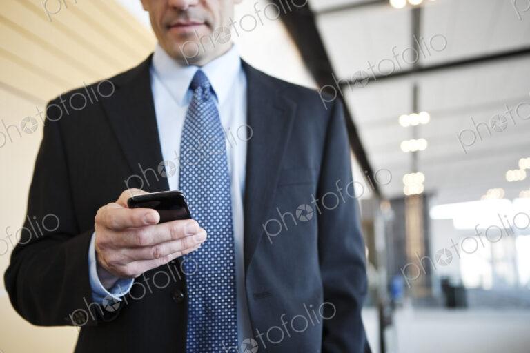 Caucasian businessman checking his cell phone in a conference centre lobby.