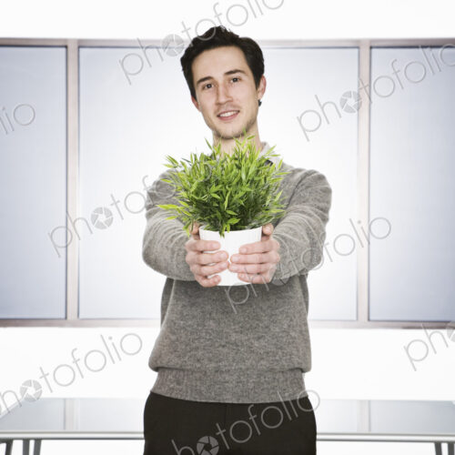 Caucasian businessman holding an office plant in his hands. Caucasian businessman holding an office plant in his hands.