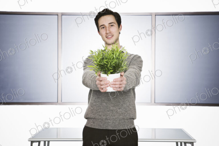 Caucasian businessman holding an office plant in his hands.