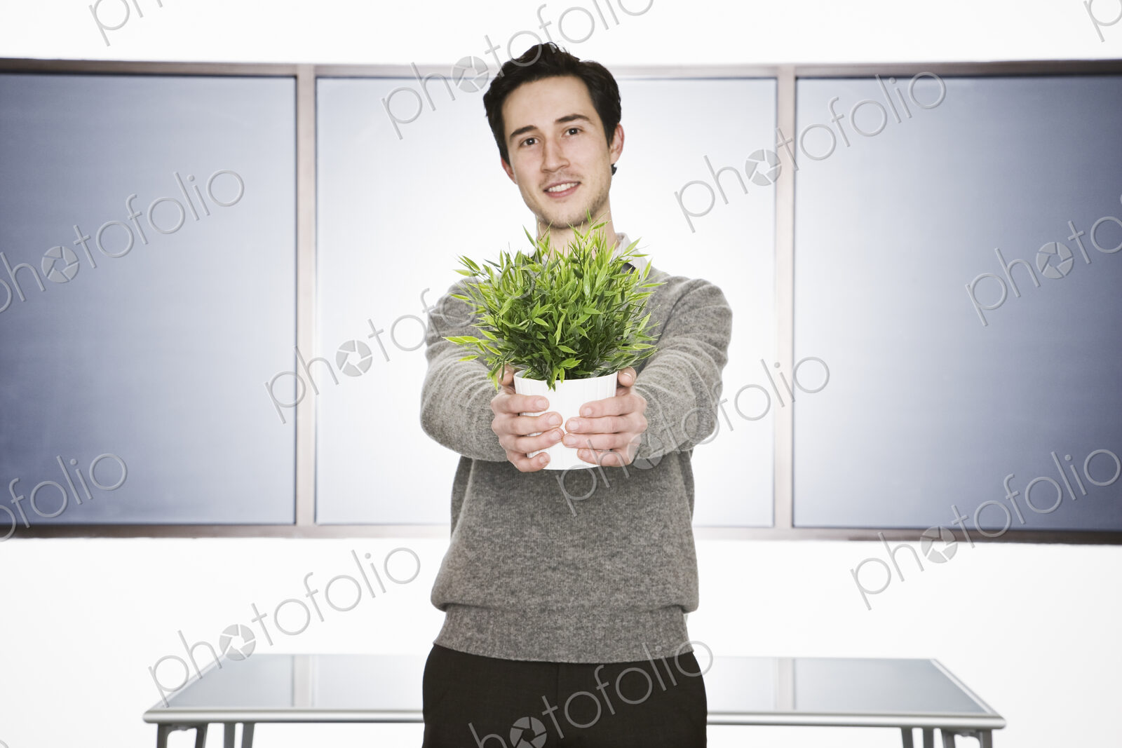Caucasian businessman holding an office plant in his hands.
