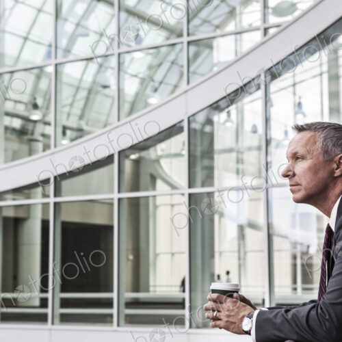 Caucasian businessman looking from a balcony near a covered walkway.