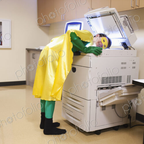 Caucasian businessman office super hero stands at photocopier, making copy of his head. Caucasian businessman office super hero stands at photocopier, making copy of his head.
