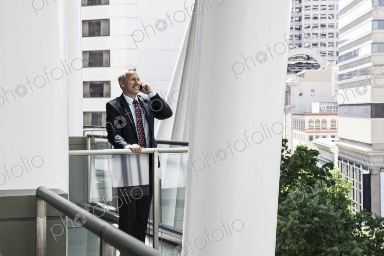 Caucasian businessman on the phone while standing on an office balcony.