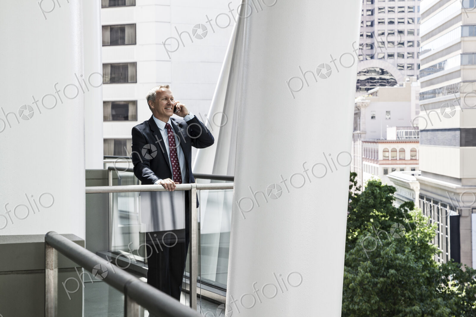 Caucasian businessman on the phone while standing on an office balcony.