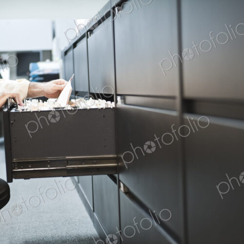 Caucasian businessman pulling files from a traditional file cabinet. Caucasian businessman pulling files from a traditional file cabinet.