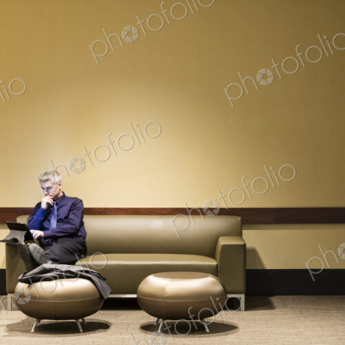 Caucasian businessman sitting at a couch working on a notebook computer. Caucasian businessman sitting at a couch working on a notebook computer.