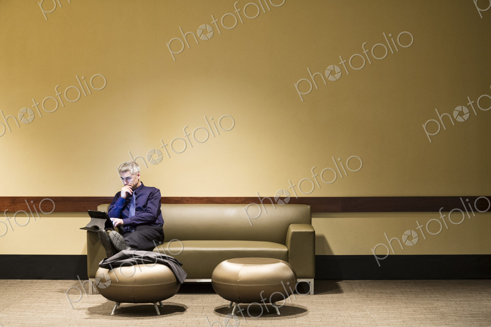 Caucasian businessman sitting at a couch working on a notebook computer.