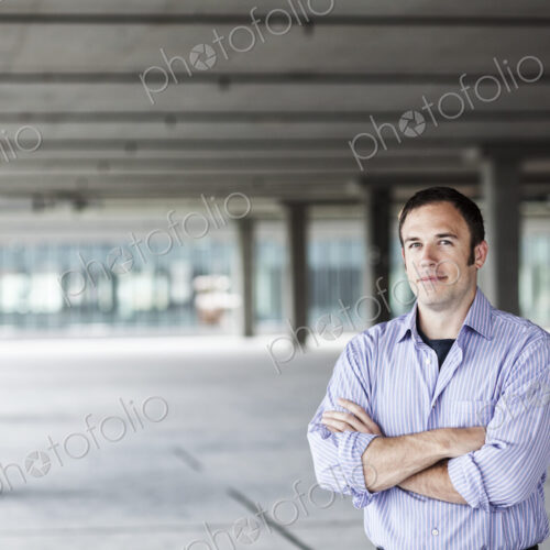 Caucasian businessman standing in a large empty raw office space.