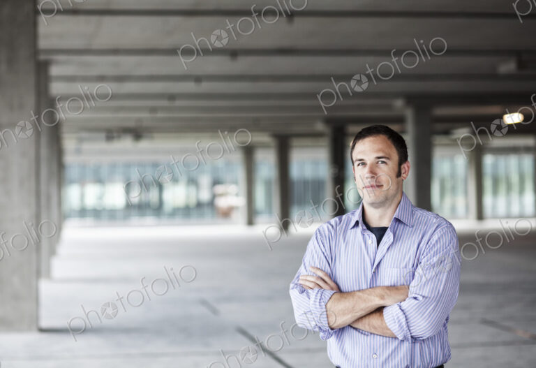 Caucasian businessman standing in a large empty raw office space.