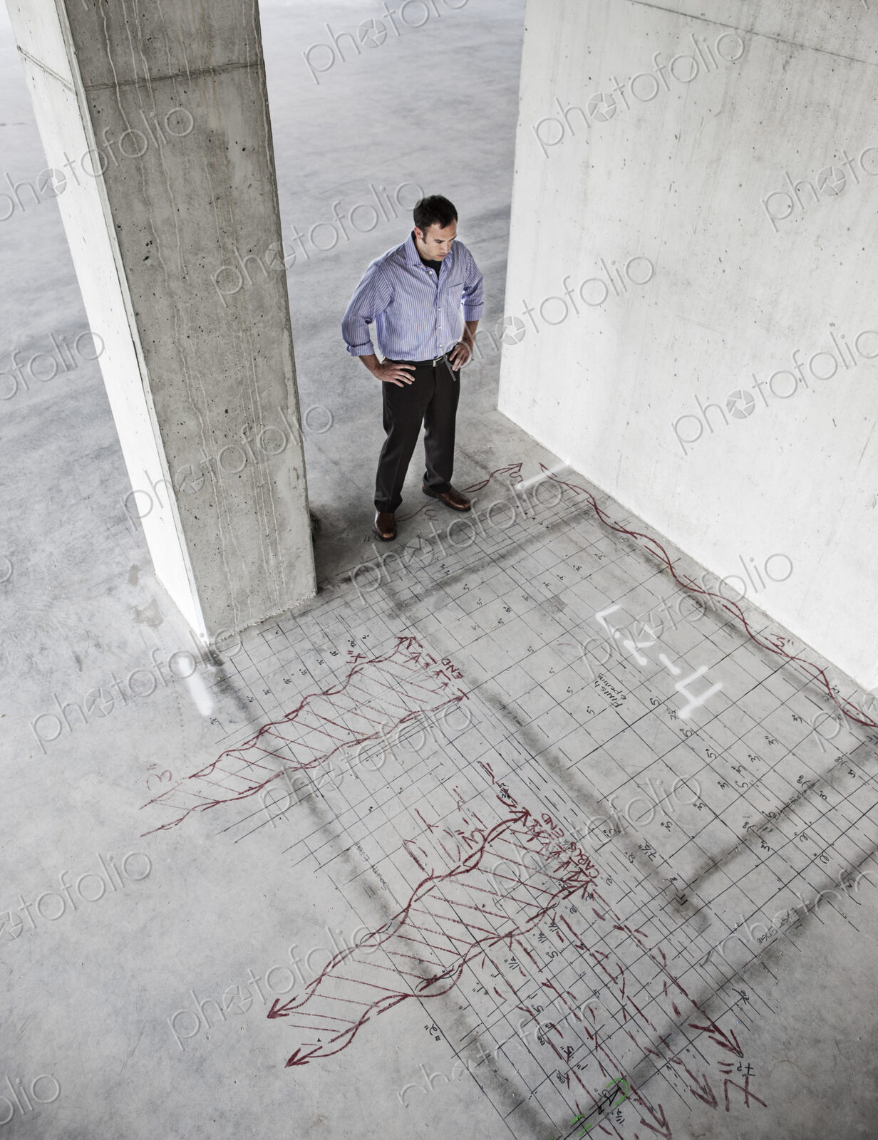 Caucasian businessman standing in a new raw office space looking at an office layout…
