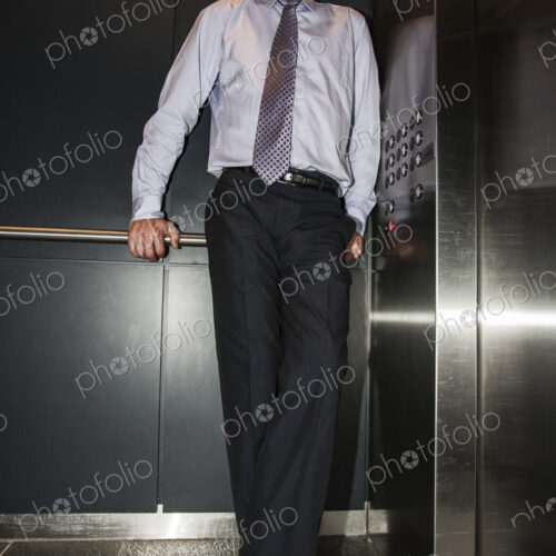 Caucasian businessman standing in the corner of an elevator in a large office building.