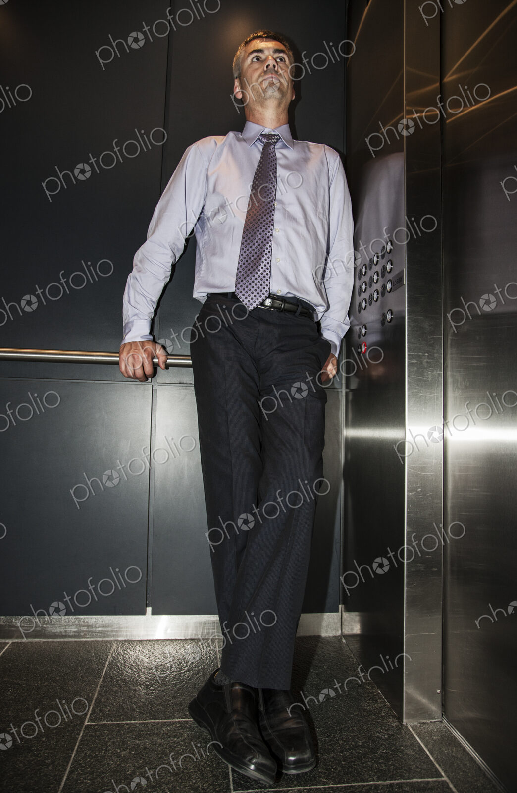 Caucasian businessman standing in the corner of an elevator in a large office building.