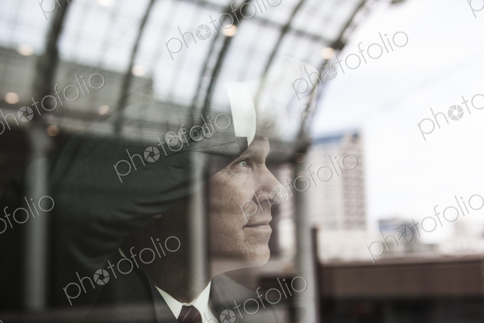 Caucasian businessman staring out a window with reflections.