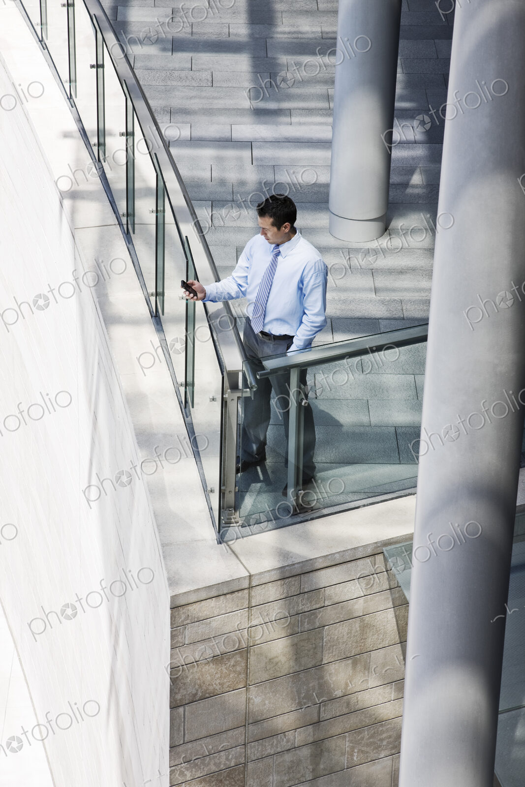 Caucasian businessman texting from a balcony on a large office building