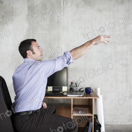 Caucasian businessman throwing a paper airplane while sitting at his desk in a raw…