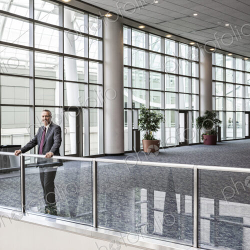Caucasian businessman waiting for an appointment standing in a large open lobby area.