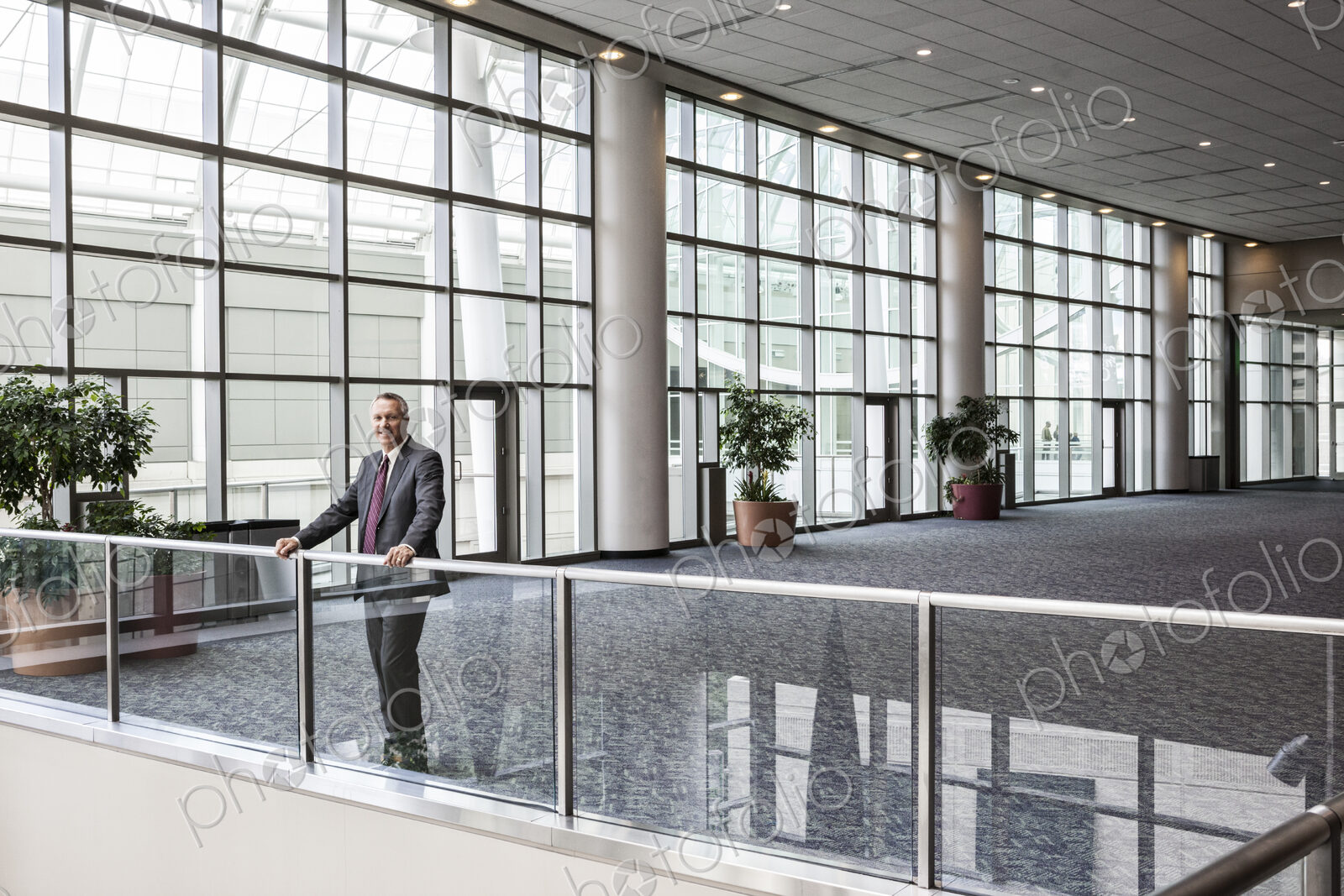 Caucasian businessman waiting for an appointment standing in a large open lobby area.