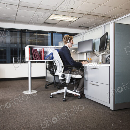 Caucasian businessman working at his computer while sitting in his cubicle office. Caucasian businessman working at his computer while sitting in his cubicle office.