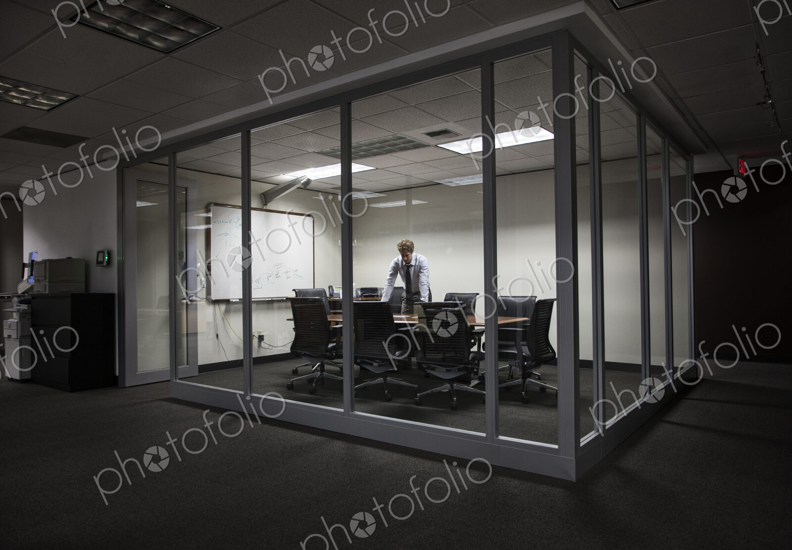 Caucasian businessman working at night in a glassed in conference room.