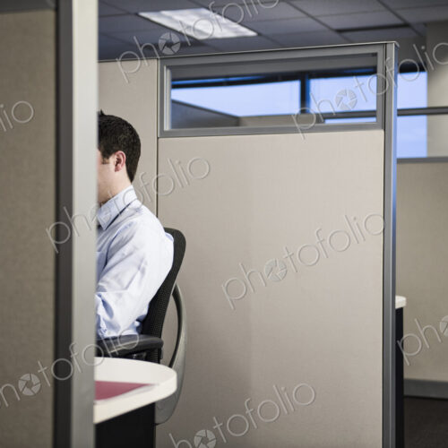 Caucasian businessman working in cubicle office.