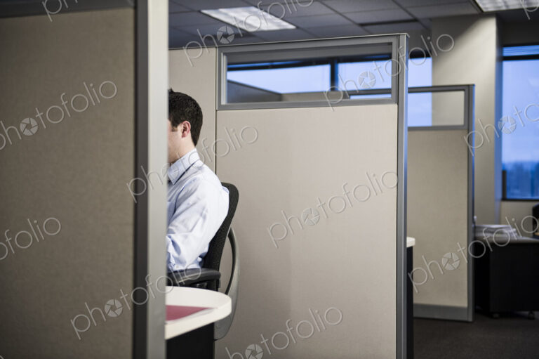 Caucasian businessman working in cubicle office.
