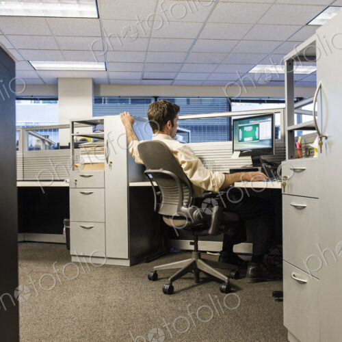 Caucasian businessman working on a computer in his cubicle office. Caucasian businessman working on a computer in his cubicle office.