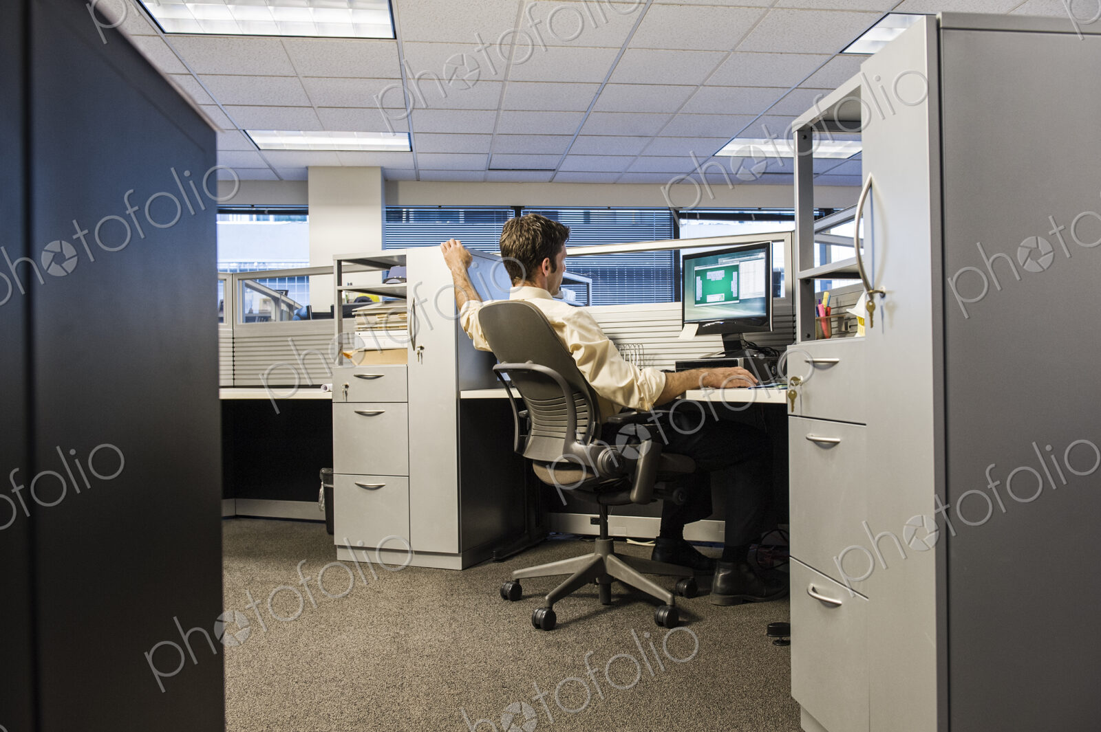Caucasian businessman working on a computer in his cubicle office.