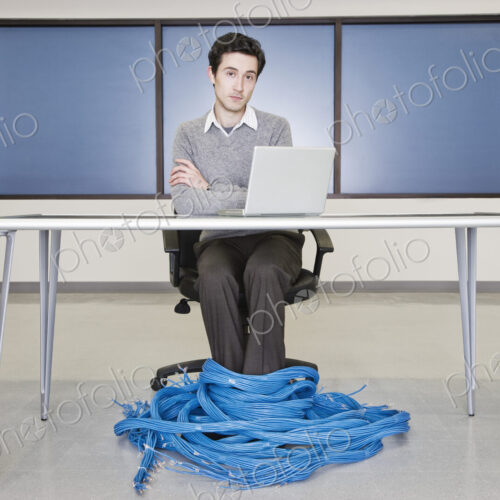 Caucasian businessman wrapped up in CAT 5 copmuter cables from a computer server farm. Caucasian businessman wrapped up in CAT 5 copmuter cables from a computer server farm.