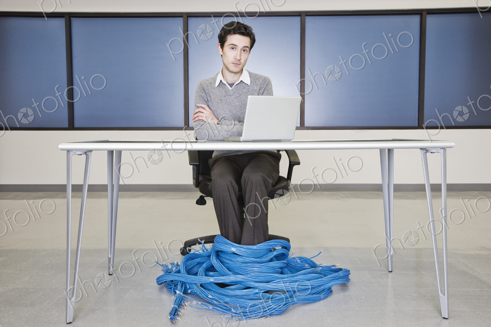 Caucasian businessman wrapped up in CAT 5 copmuter cables from a computer server farm.