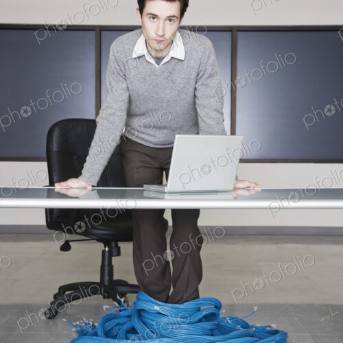 Caucasian businessman wrapped up in CAT 5 copmuter cables from a computer server farm. Caucasian businessman wrapped up in CAT 5 copmuter cables from a computer server farm.