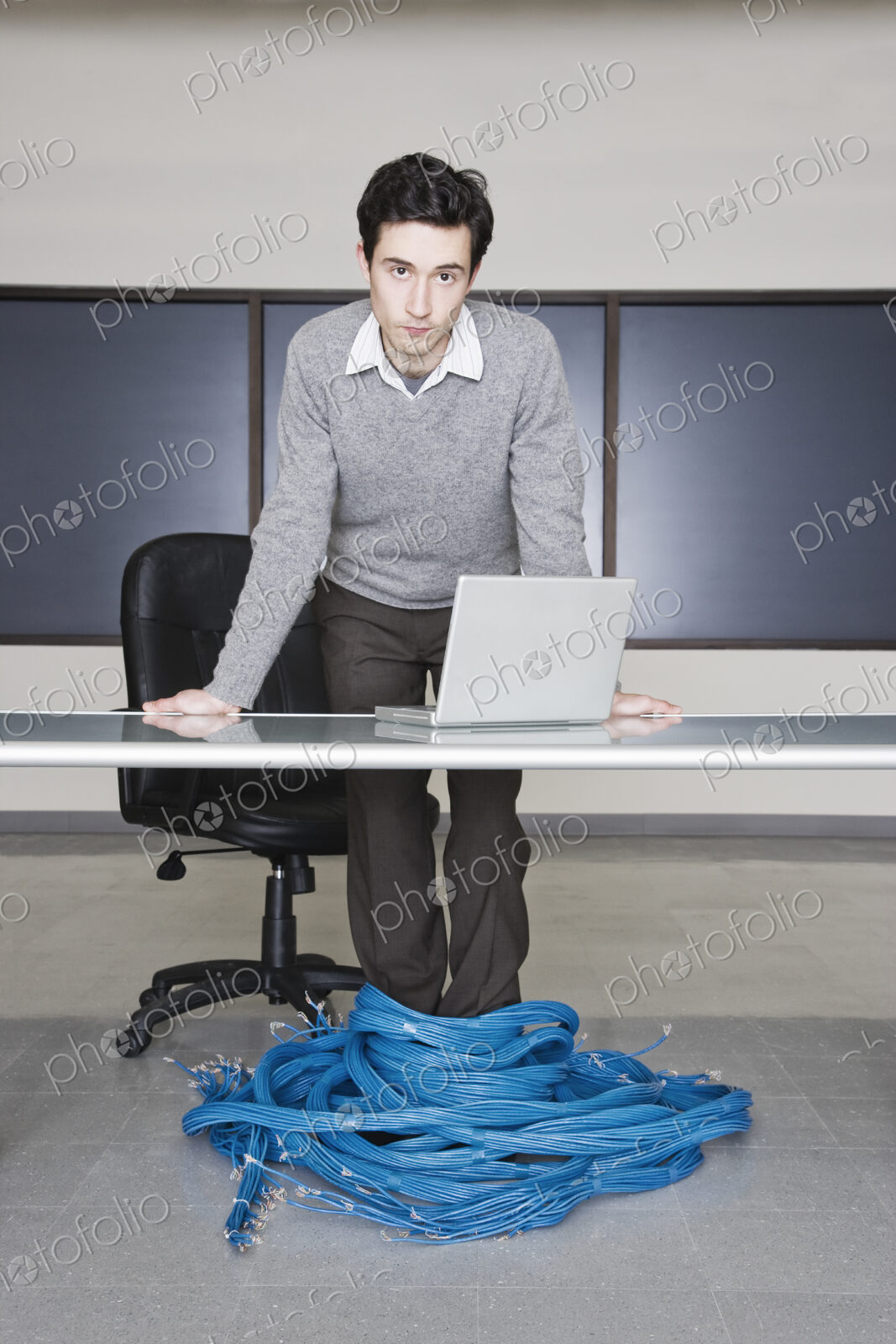 Caucasian businessman wrapped up in CAT 5 copmuter cables from a computer server farm.
