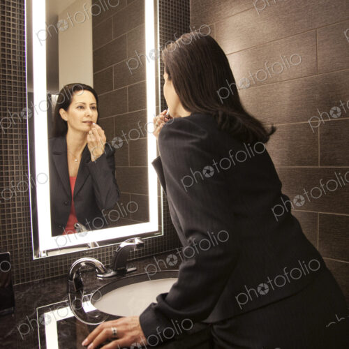 Caucasian businesswoman doing makeup in a mirror. Caucasian businesswoman doing makeup in a mirror.