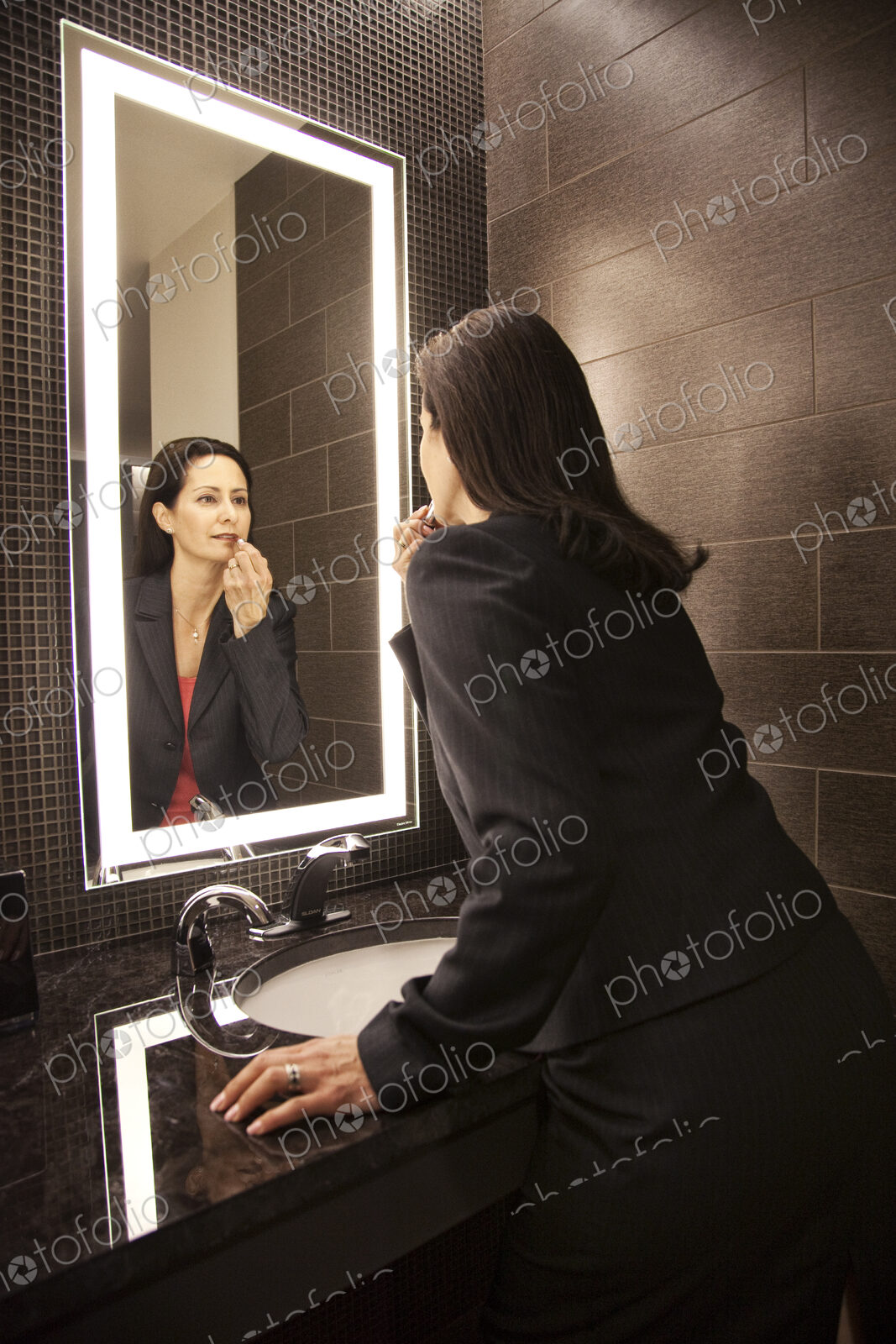 Caucasian businesswoman doing makeup in a mirror.