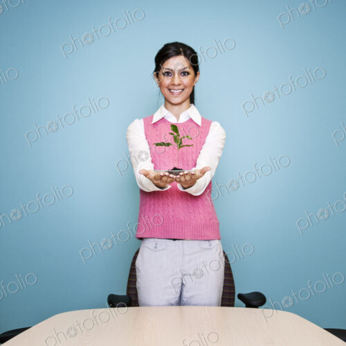 Caucasian businesswoman holding a plate with a single plant seedling. Caucasian businesswoman holding a plate with a single plant seedling.