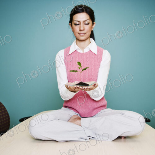 Caucasian businesswoman holding a plate with a single plant seedling. Caucasian businesswoman holding a plate with a single plant seedling.