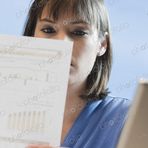 Caucasian businesswoman looking over paperwork. Caucasian businesswoman looking over paperwork.