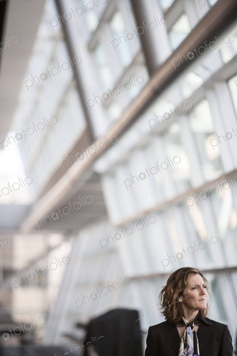 Caucasian businesswoman pausing for a moment near a large window in a conference…