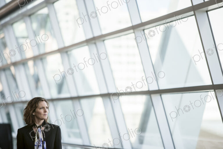 Caucasian businesswoman pausing for a moment near a large window in a conference…