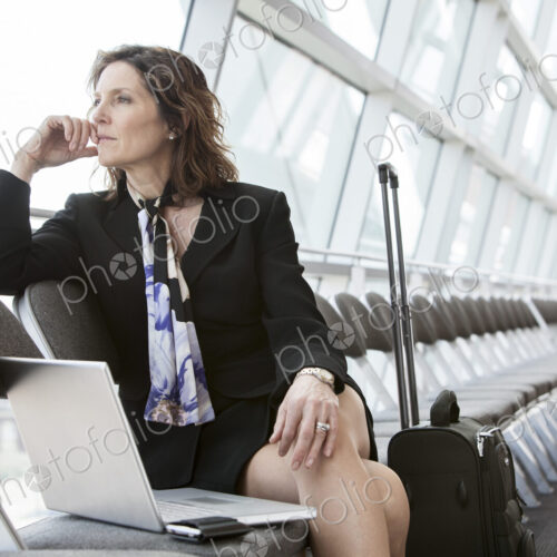 Caucasian businesswoman sitting in a row of chairs against a window in a conference… Caucasian businesswoman sitting in a row of chairs against a window in a conference…
