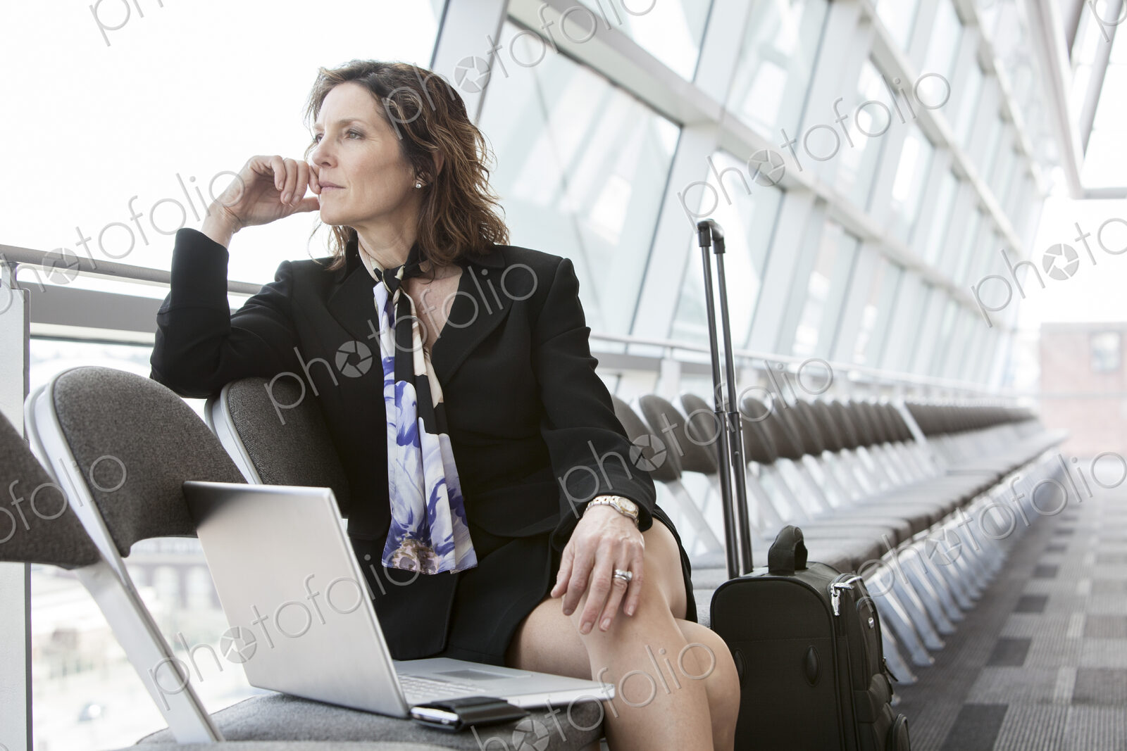 Caucasian businesswoman sitting in a row of chairs against a window in a conference…