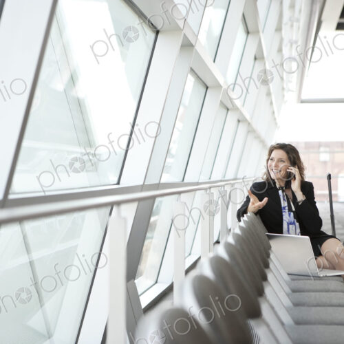 Caucasian businesswoman using her cell phone, sitting alone Caucasian businesswoman using her cell phone, sitting alone