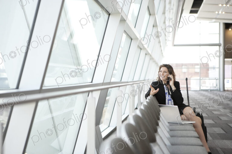 Caucasian businesswoman using her cell phone, sitting alone