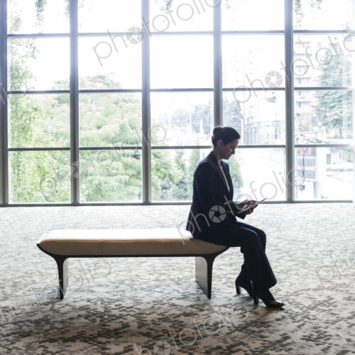 Caucasian businesswoman working on a computer while sitting on a bench in a business… Caucasian businesswoman working on a computer while sitting on a bench in a business…