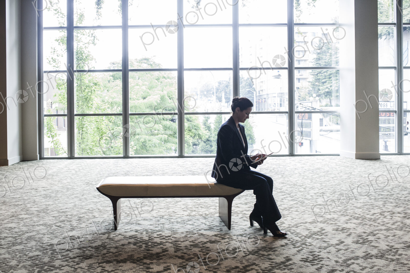 Caucasian businesswoman working on a computer while sitting on a bench in a business…