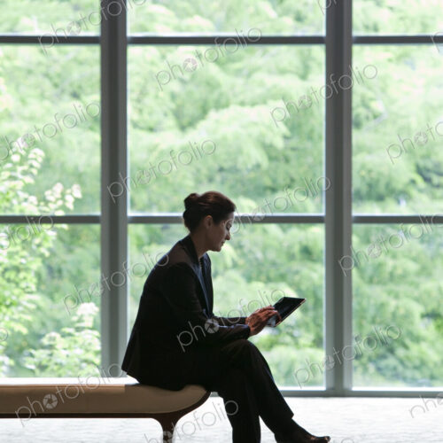 Caucasian businesswoman working on a computer while sitting on a bench in a business… Caucasian businesswoman working on a computer while sitting on a bench in a business…
