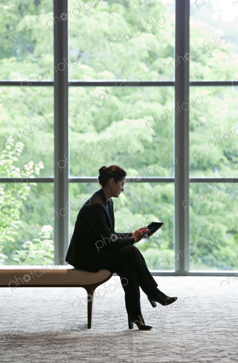 Caucasian businesswoman working on a computer while sitting on a bench in a business…