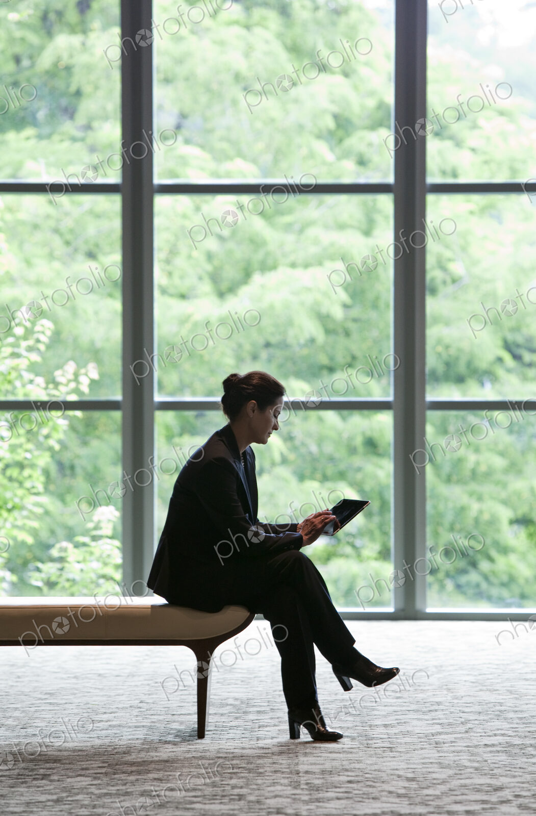 Caucasian businesswoman working on a computer while sitting on a bench in a business…
