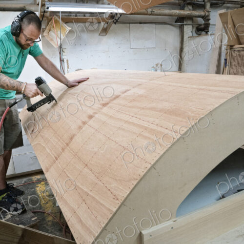 Caucasian carpenter working on a curved staircase in a large woodworking shop. Caucasian carpenter working on a curved staircase in a large woodworking shop.