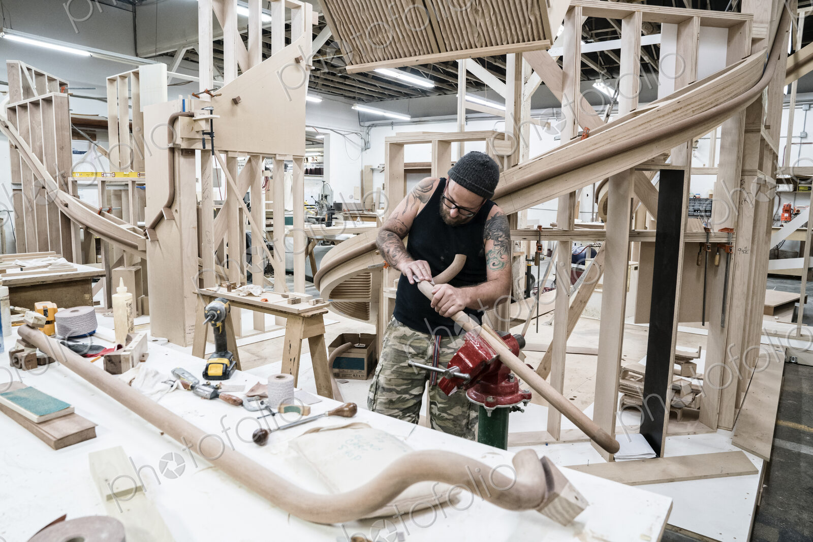 Caucasian carpenter working on a spiral staircase railing in a large woodworking shop.