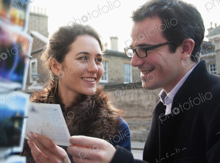 Caucasian couple admiring postcards in gift shop